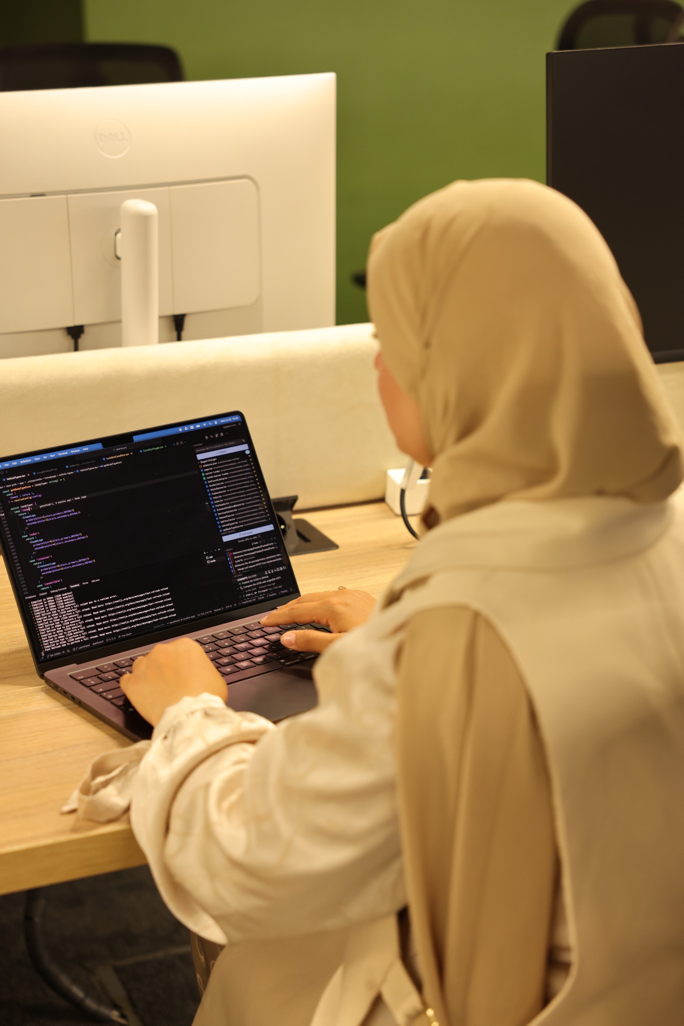 Amira working on frontend code at her laptop